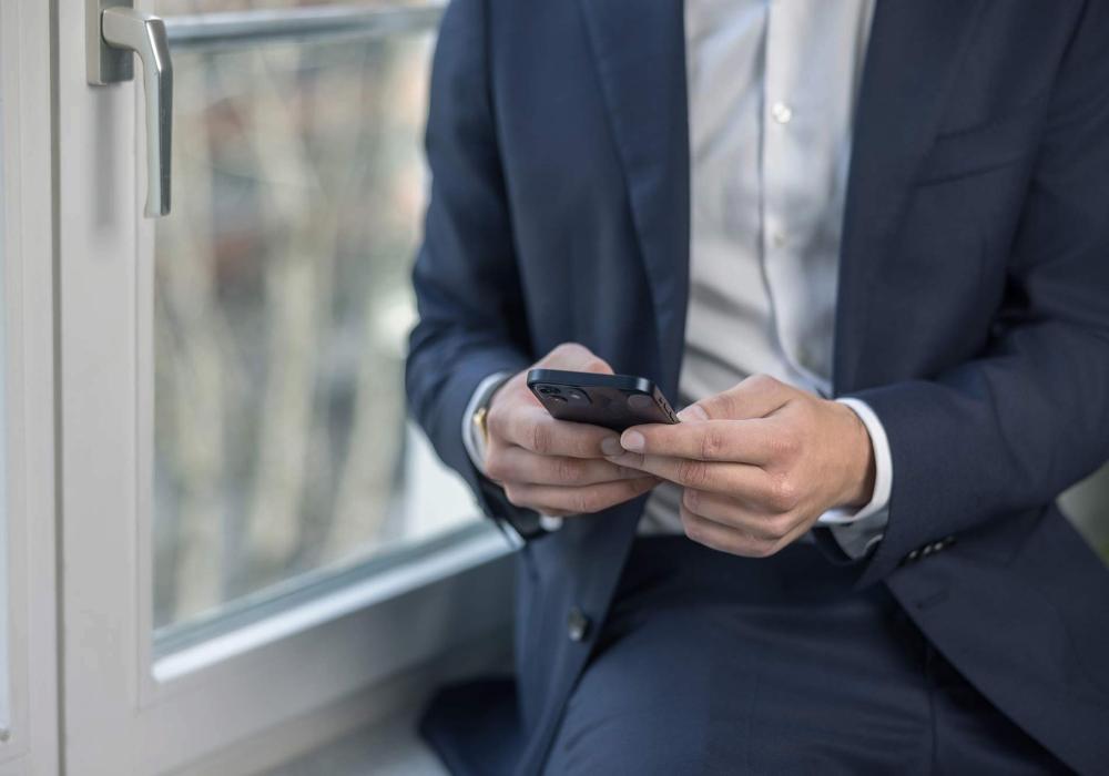 Eine Person im Anzug mit Handy in der Hand
