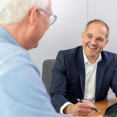 Vermögenspartner Mario Wolf lachend im Gespräch mit einem Kunden