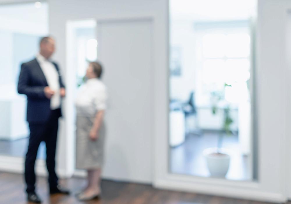 Ein unscharfes Bild mit zwei Mitarbeitenden im Hintergrund